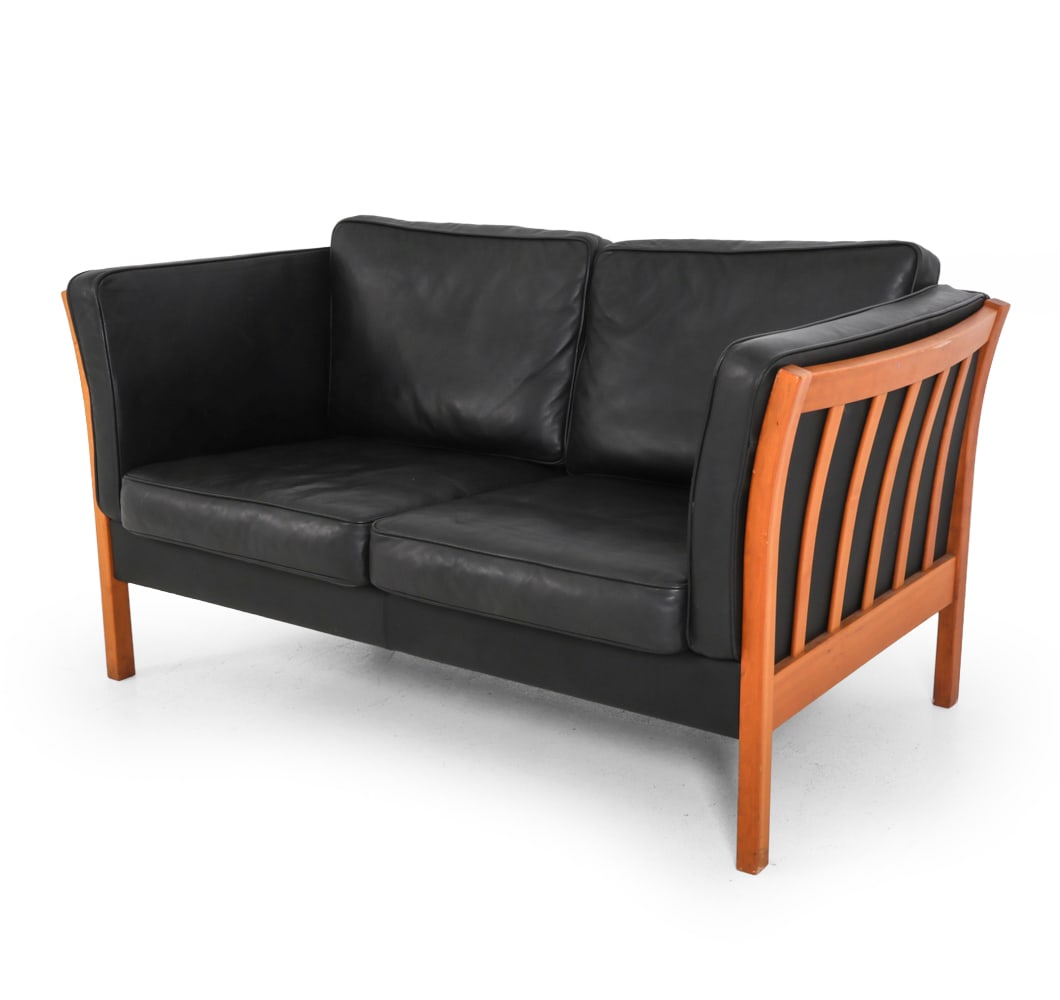 STOUBY DANISH LEATHER LOVESEAT SOFA C. 1970S: Marked underneath cushions. Black leather cushions with slatted frame. Denmark, circa 1970s. Dimensions: H 30" x W 56" x D 32" S.H. 17" Condition: Showing signs of wear including scratches, scuffs to