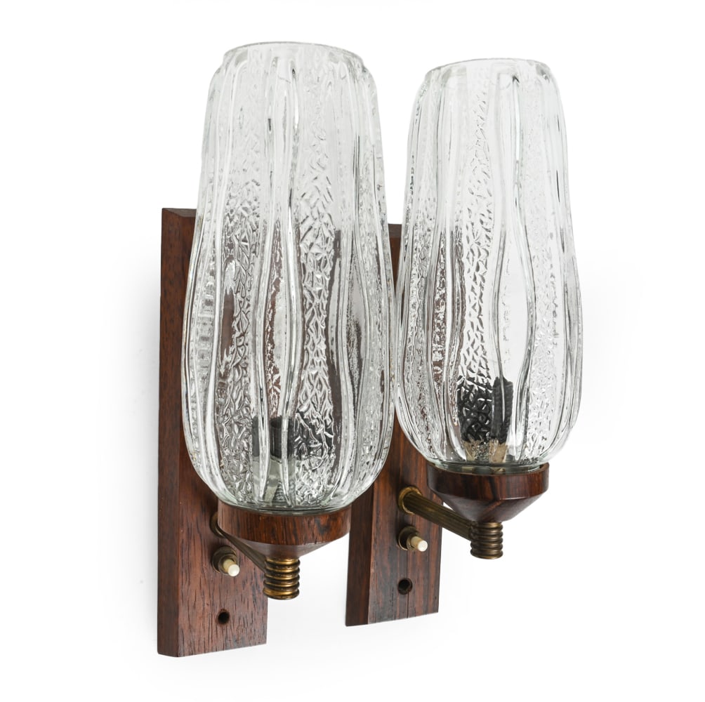 PAIR OF DANISH ROSEWOOD WALL SCONCES C. 1960S: Teak with brass arm and molded glass shade. Denmark, circa 1960s. Dimensions: H 11.25" x W 3.5" x D 5" Condition: Scuffs, Split to wood on wall mount to one sconce, wear consistent with age and use.