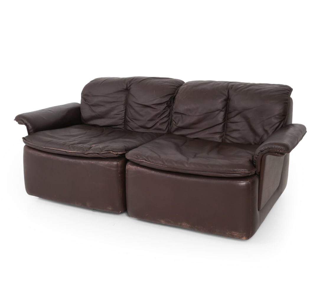 STYLE OF DE SEDE SWISS LEATHER LOVESEAT SOFA 1970S: Dark brown leather with broad padded arms and low profile box form. Apparently unmarked. Switzerland, circa 1970s. Dimensions: H 27? x W 65? x D 36", SH 16.5" Condition: Impressions to leather on