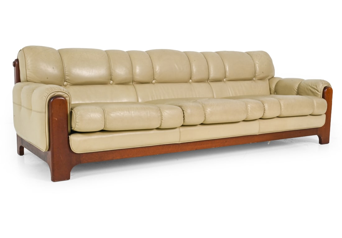 EKORNES STYLE NORWEGIAN LEATHER SOFA C. 1970S: Channel tufted cream leather upholstery with rounded arm cushions. Stained beech frame. Norway, circa 1970s. Dimensions: H 29.5" x W 92" x D 36.25" x SH 16" Condition: Fading/discoloration.