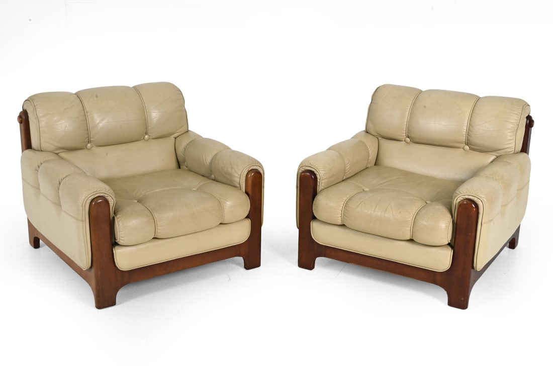 PAIR OF EKORNES STYLE LEATHER LOUNGE CHAIRS 1970S: Cream leather upholstery with padded backs, rolled arms and stained beech sides. Norway, circa 1970s. Dimensions: H 29" x W 33.75" x D 36" x SH 15.5" Condition: Scuffs and scrapes to frames.
