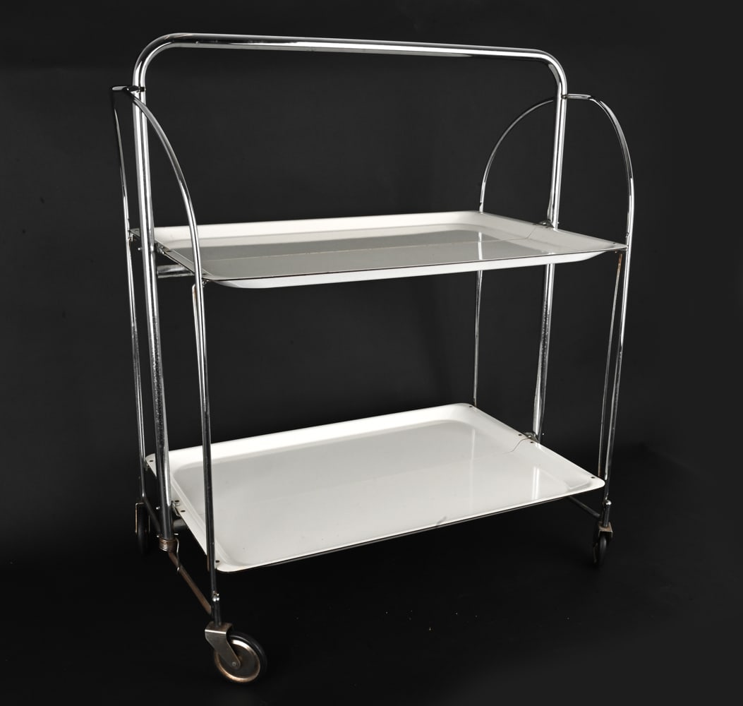 BREMSHEY "DINETT" GERMAN CHROME BAR CART C. 1970S: Folding bar cart or serving trolley with tubular chrome frame and white plastic shelves. Can be folded flat for storage. Apparently unmarked. Germany, circa 1970s. Dimensions: H 30.5" x W 27" x D