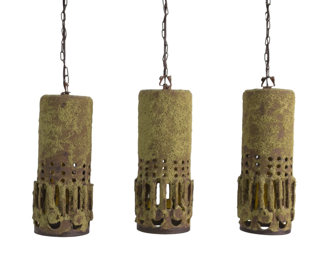 MID-CENTURY CERAMIC PENDANT LIGHTS C. 1960S: Grouping of three matching ceramic pendant lamps with a brutalist design and cut-out holes. Apparently unmarked. Dimensions: H 12.75" x Dia 5" Condition: Untested. Scuffs to bottom rims, wear