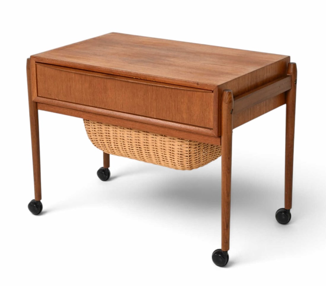 MID-CENTURY DANISH TEAK SEWING TABLE C. 1960S: Teak sewing table with storage compartment and rolling caster base. Apparently unmarked. Denmark, Circa, 1960s. Dimensions: H 20.75" x W 28.25" x D 16" Condition: Some scuffs with scratches, watermark