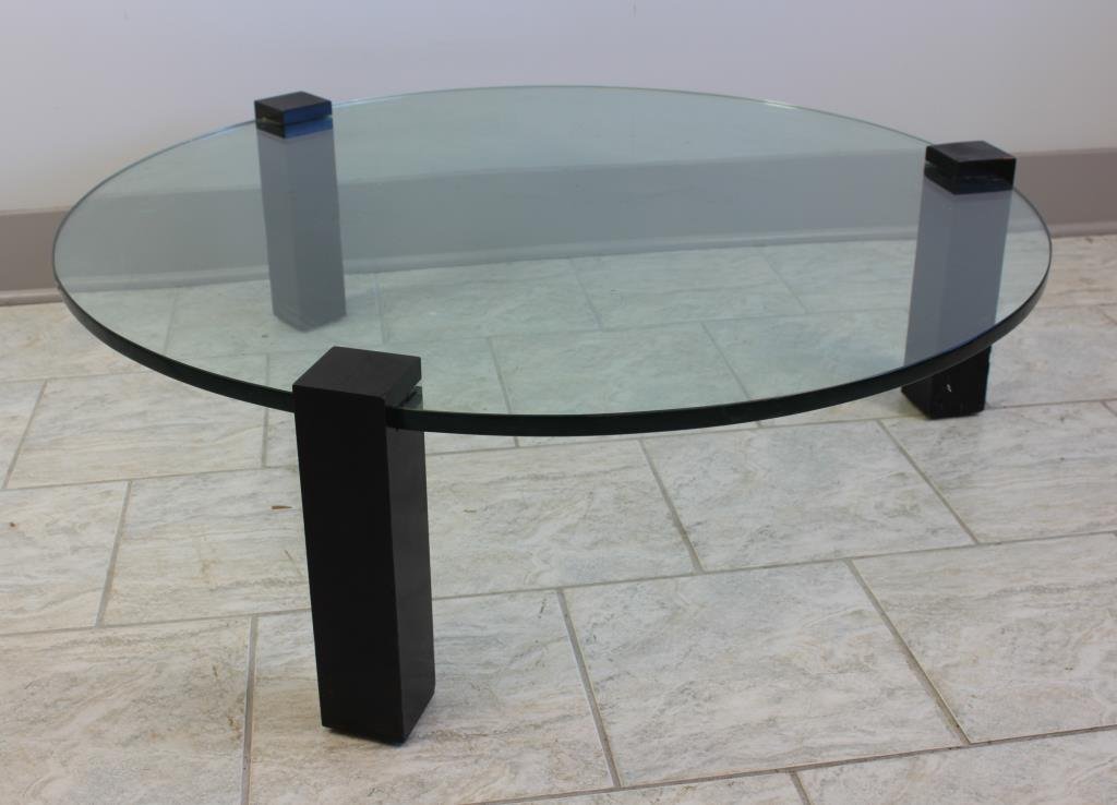 MID-CENTURY GLASS COFFEE TABLE: Ebonized wood and glass Dimension: H 13.5" X Dia: 42" Condition: Good, some chips to wood base