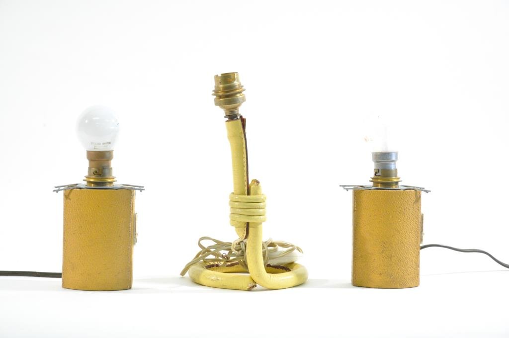 3 JACQUES ADNET TABLE LAMPS: Pair of small table lamps and a singular table lamp, all with bayonet sockets and european plugs, leather wrapped and weighted, unmarkedDimensions: (Single) H 8.5" X W 6" X D 5"Dimensions: (Pair) H 7"