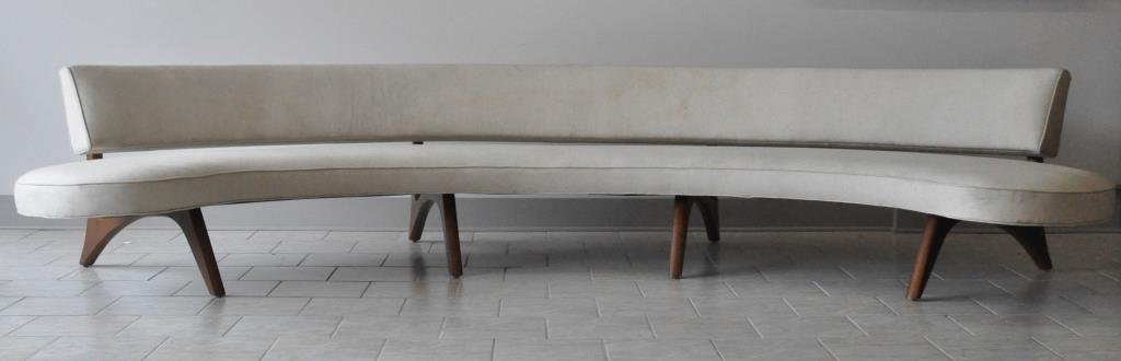 MID-CENTURY FLOATING SOFA MANNER OF VLADIMIR KAGAN: C. 1960s, an upholstered crescent sofa supported by angular legsDimensions: H 30" x W 140" x D 60"Condition: good, some stains to upholstery