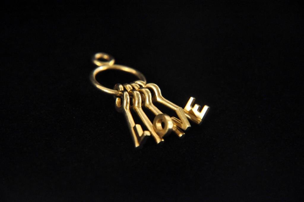 TIFFANY & CO 18K GOLD LOVE KEY DANGLE CHARM: Marked K18 Italy Tiffany. Four keys on a ring spell out Love at the bottoms. Dimensions: L 1.75" X W 0.70"Weight: 7.3dwtCondition: Very good