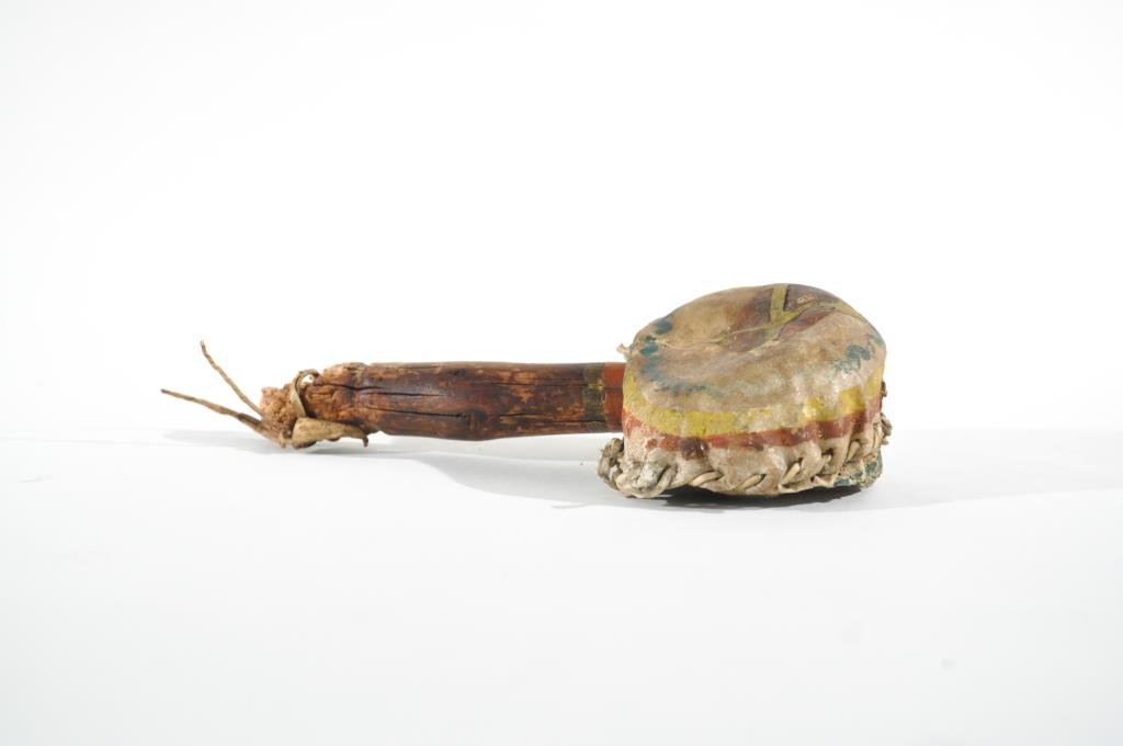 NATIVE AMERICAN RATTLE: Painted rawhide, wood and stones. Dimensions: L 9" X W 4.5"Condition: Hardened hide, chips to handle.
