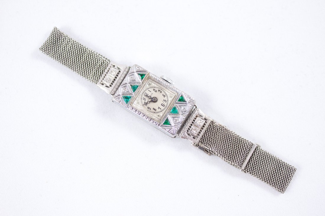 BULOVA 10K GOLD, DIAMOND, & EMERALD LADIES WATCH: 10k white gold mesh band with 10k etched gold, diamond and emerald case. Movement number 13985 15 jewels, case number 8383165 dated 1924.Dimensions: W .5", adjustable bandTotal Weight: 18.9 gCondition