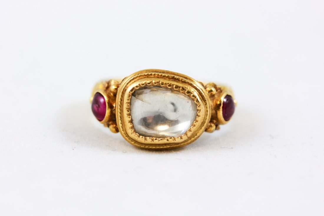 ANTIQUE 22K GOLD, DIAMOND & RUBY RING: Approx 1 carat center diamond with 2 Burma ruby cabochons flanking Ring Size: 6 Face: 0.75" x 0.50"Total weight: 7.1g Condition: Good, imperfection on underside of diamond.