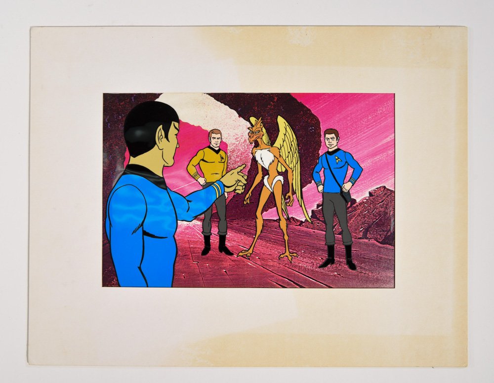 STAR TREK: THE ANIMATED SERIES FILM CELL: Film cell titled "Yesteryear", featuring members of the crew with a alien life form on a plastic sheet, with a matte painting of a alien world. This cell was used by the team producing the animated se