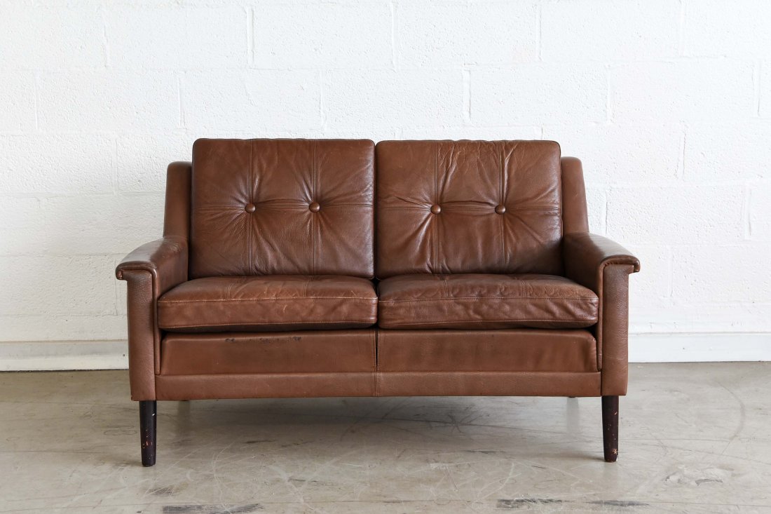 TWO-SEAT LEATHER SOFA: Dimensions: H 28" x W 48" x D 35" Condition: light wear to upholstery, some creasing, scuffs to legs