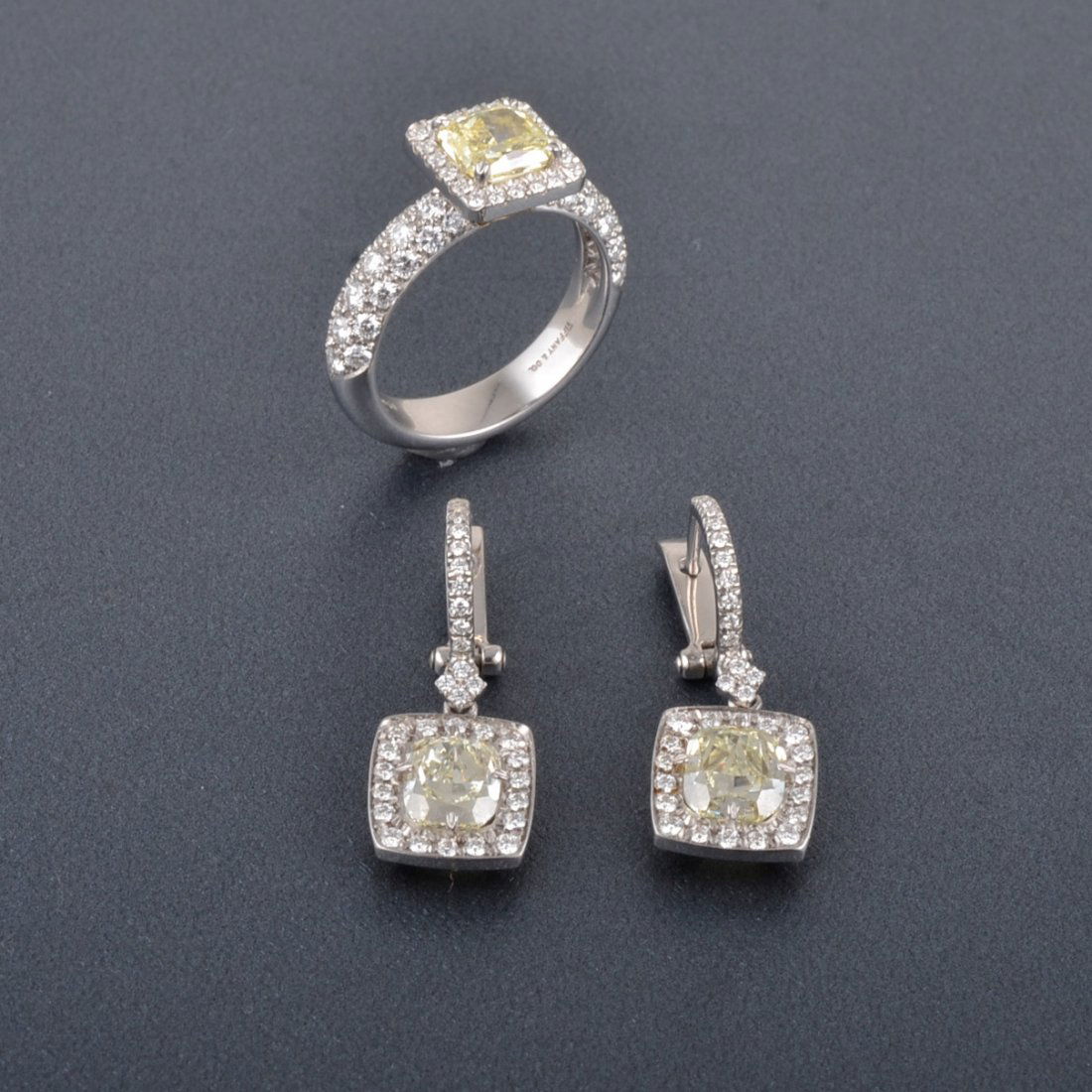 Tiffany Yellow Diamond Earring and Ring Suite: Tiffany platinum and yellow gold yellow diamond ring and earrings. The earrings each set with a cushion cut yellow diamond weighing approx. 1.15ct in the center and surround with 18 full cut diamonds