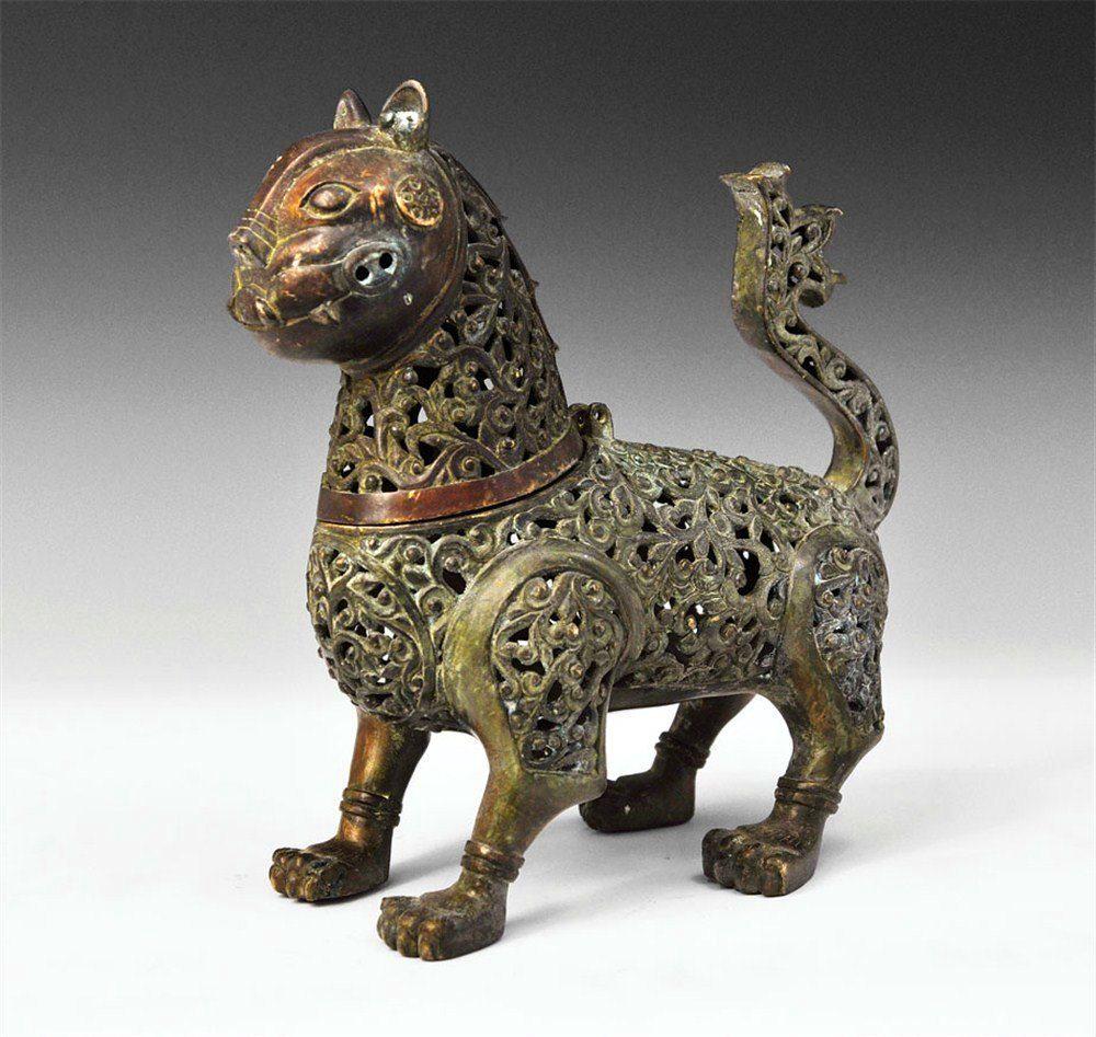 Islamic Bronze Lion Incense Burner: Early 20th century copy of an Islamic 12th-century-style openwork censor, formed as a standing lion with raised tail, ribbed paws, and grotesque face with erect ears. The head is hinged to the rear of