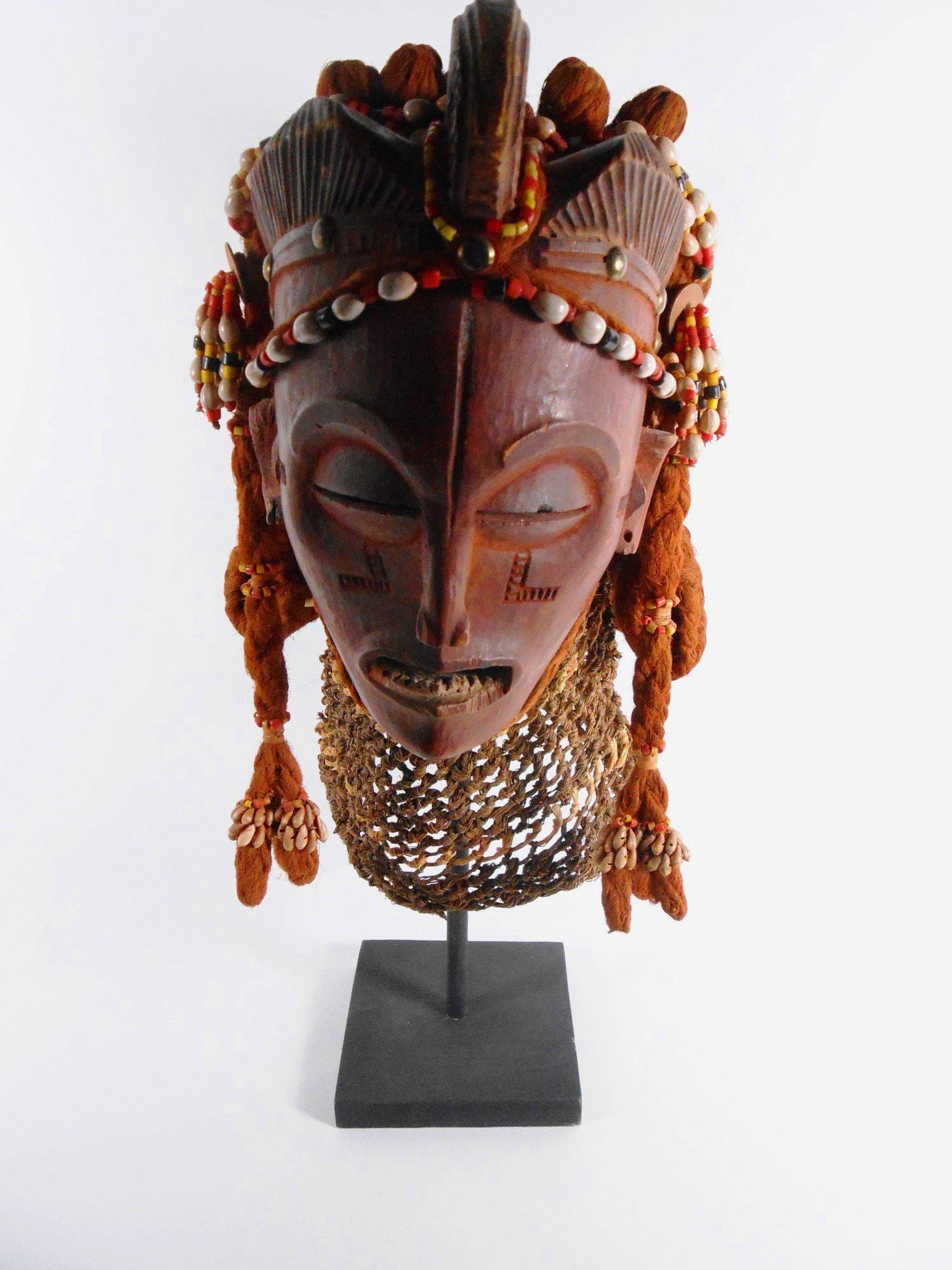 Chokwe Mwana Pwo Ritual Mask: African Chokwe Mwana Pwo Mask, having a carved wooden face with dark red pigment and scarification marks, the whole decorated with shells and colored beads, twisted twine hair and a woven raffia cowl.
