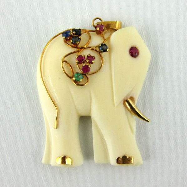 Carved Ivory and 14KT Gold Elephant Pendant: 14KT gold decoration with rubies, sapphires, and an emerald. One tusk is missing. A gift to the present owner by Gene Moore. Gene Moore (1910-1998) was vice-president of window display at Tiffany & Co
