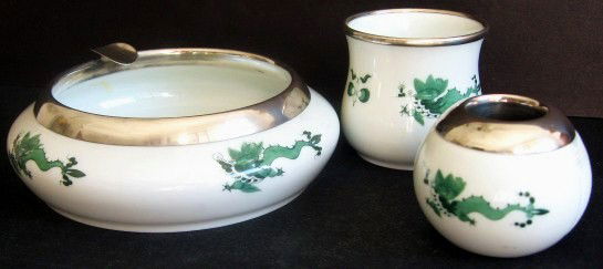 Meissen Smoking Set: Three pieces of Meissen, each having a sterling silver rim. Ashtray, cigarette holder, and match holder. Green Dragon pattern. Ashtray diameter: 5 1/2 inches. H (cigarette holder): 2 1/2 inches. H (ma