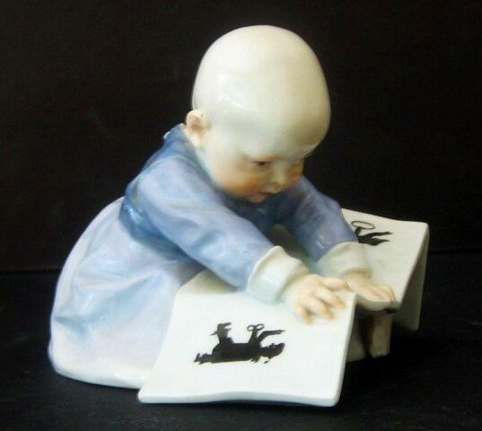 Meissen Baby Holding A Book: Very scarce Meissen figure of a seated baby holding a book. Characteristic Meissen crossed swords mark and incised mold number. H. 4 inches. W. 5 inches.