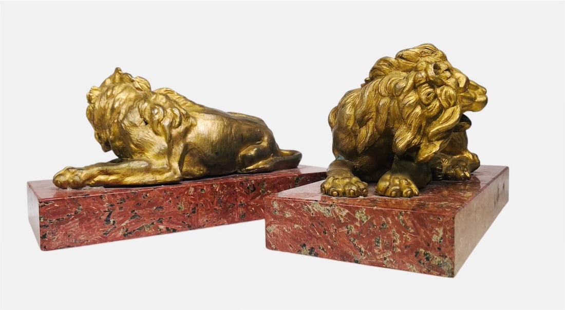 Gilt-Bronze Lions On Rouge Marble Bases: Fine pair of gilt-bronze recumbent lions on rouge marble bases, 19th century. No apparent signature. H. 4 3/4 inches W. 9 1/8 inches D. 4 1/4 inches. Provenance: Sotheby's, New York, Sale N06966, Lot 