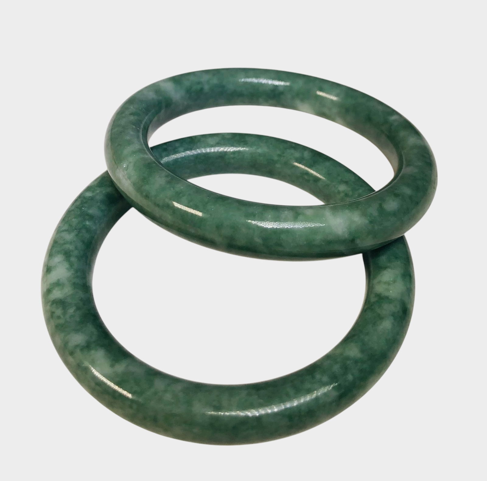 Two Green & White Chinese Jade Bangle Bracelets: Two mottled green and white Chinese jade bangle bracelets, late 20th century. Dia. (each) 3 inches