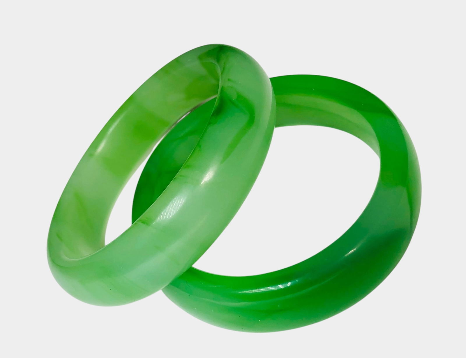 Two Apple Green Chinese Jade Bangle Bracelets: Two near apple green Chinese bangle bracelets, circa 1950-1960. Dimensions: Dia. (largest) 3 1/4 inches