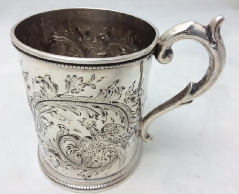 Sterling Mug, Wood & Hughes, NY, circa 1860: Wood & Hughes, New York, New York, circa 1860. Marks: WOOD & HUGHES (struck twice). 4 3/8" high. 5.39 troy ounces. The mug with beaded borders at rim and foot, with repousse bird and foliate scroll de