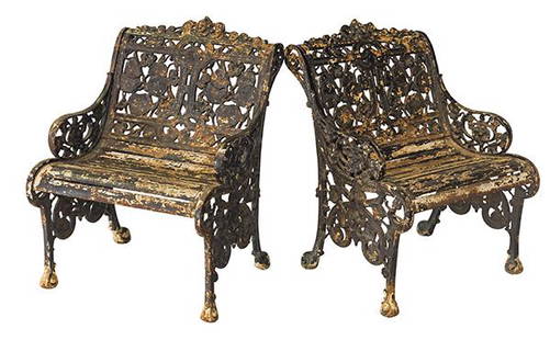 Pair of Iron Garden Benches: Ornate cast iron benches with embossed center heads and floral motif. Iron slat seats and scrolled side aprons. 25 1/2w x 27d x 34h.