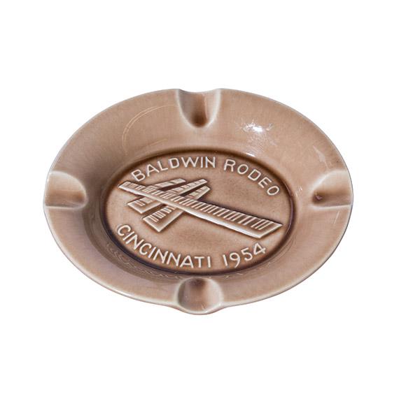 Rookwood Baldwin Rodeo Ashtray: Tan and brown high glaze Rookwood ashtray advertising Baldwin Rodeo Piano Cincinnati 1954. Marked with the Rookwood logo, dated 1954. 6 1/4" Diameter
