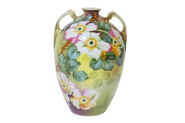 Ovoid Nippon Vase with Glossy Flowers Marked: Nippon Porcelain floral vase, ovoid form with a high shoulder, molded handles, elaborate hand painted flowers and large green leaves with a glossy finish. Vines of green leaves cover the backside. Bri