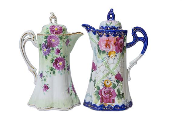 Two Nippon Chocolate Pots: Two Chocolate Pots with floral design. One has purple and pink flowers with green leaves. Gild trim around lid, handle and rim. 5 1/4" Dia x 9 " H. Other pot has cobalt blue design with beautiful colo