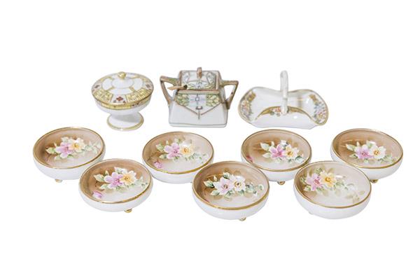 Ensembled Nippon Porcelain Group: Grouping of Nippon including (1) lidded Trinket Box, (1) Basket with handle and folded rim , (1) Square Mustard with moriage detailing and gold spoon and (1) Seven footed Salts (1 has hairline) with p