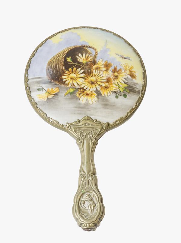 G.Silver Porcelain Hand Mirror: Victorian Porcelain Mirror with hand painted daises falling out of a basket. Background of yellow and gray. Cherub and scrolled embossed decorated handle and beveled mirror. Marked G. Silver 5" W x 9 