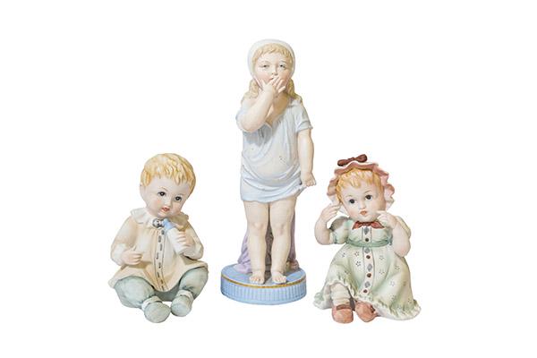 German Bisque Piano Babies & Figurine: Vintage 2 Porcelain bisque seated boy & girl Piano Baby Figurines marked Germany. 4" w x 6" H. Bisque Girl with hand up to her mouth standing on round blue base leaning on purple pedestal. 3 1/2" x 10