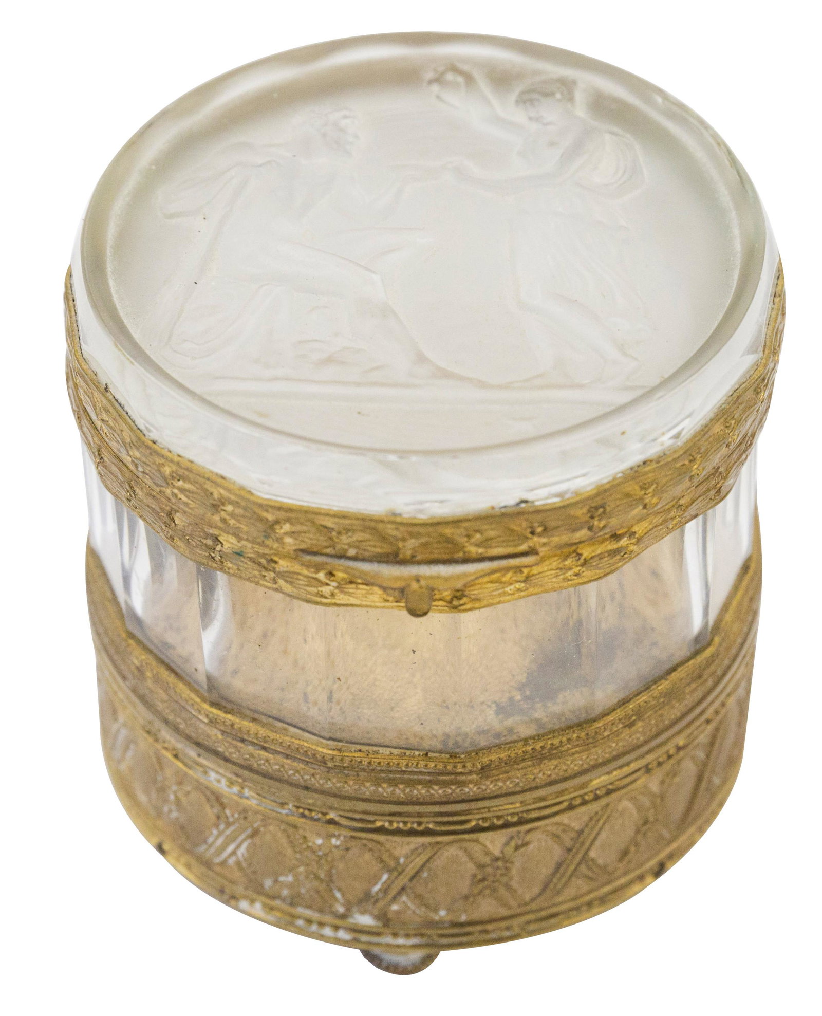 Signed French Crystal Hinged Lid Music Box: Circa 1940 four hinged lid music box with embossed man and woman to lid with brass embossed leaf borders. Thick crystal center over a beaded brass border and embossed floral and leaf garland. Signed t