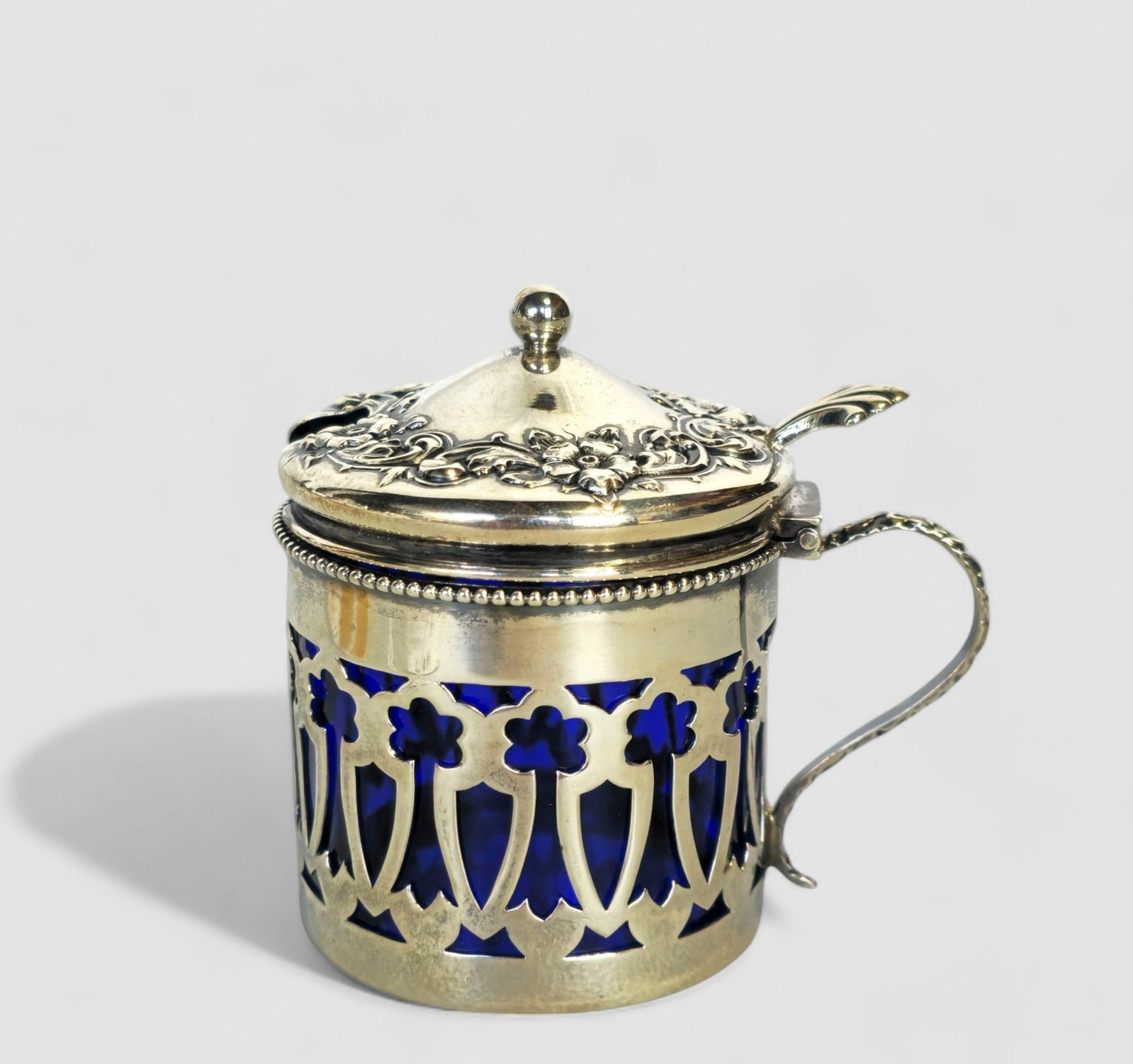 Sterling Silver & Cobalt Blue Mustard Jar: Sterling Silver & Cobalt Blue Mustard Jar, curved handle and hinged lid with embossed flowers. Open work art nouveau floral design. Original glass cobalt blue liner. Marked sterling and #110. 2 1/8dia