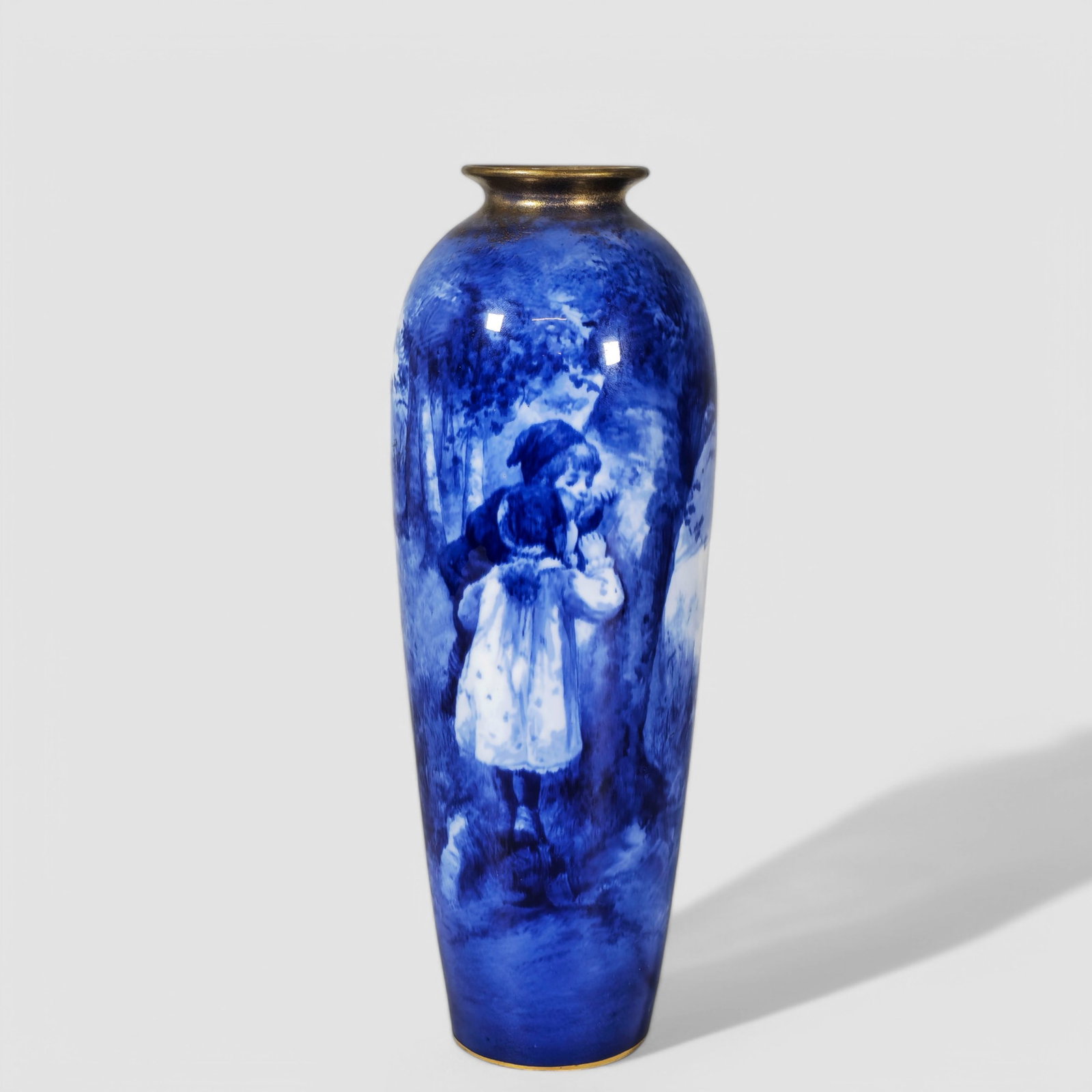 Royal Doulton Scenic Porcelain Vase: Royal Doulton Scenic Porcelain Vase, girl and boy peeking through the trees. The other side has a beautiful scenic view of lake. Manufacturer's mark to underside. 3 3/4dia x 11h