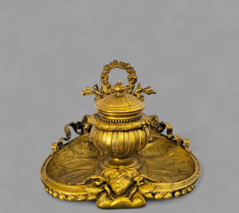 19th Century Gilt Bronze Inkwell: 19th Century Gilt Bronze Inkwell, circa 1840-1860. Wreath on leaves center pedament. Flanked by dangling ribbons. Ink well in urn form with hinged lid and porcelain liner. Heart shaped base with high