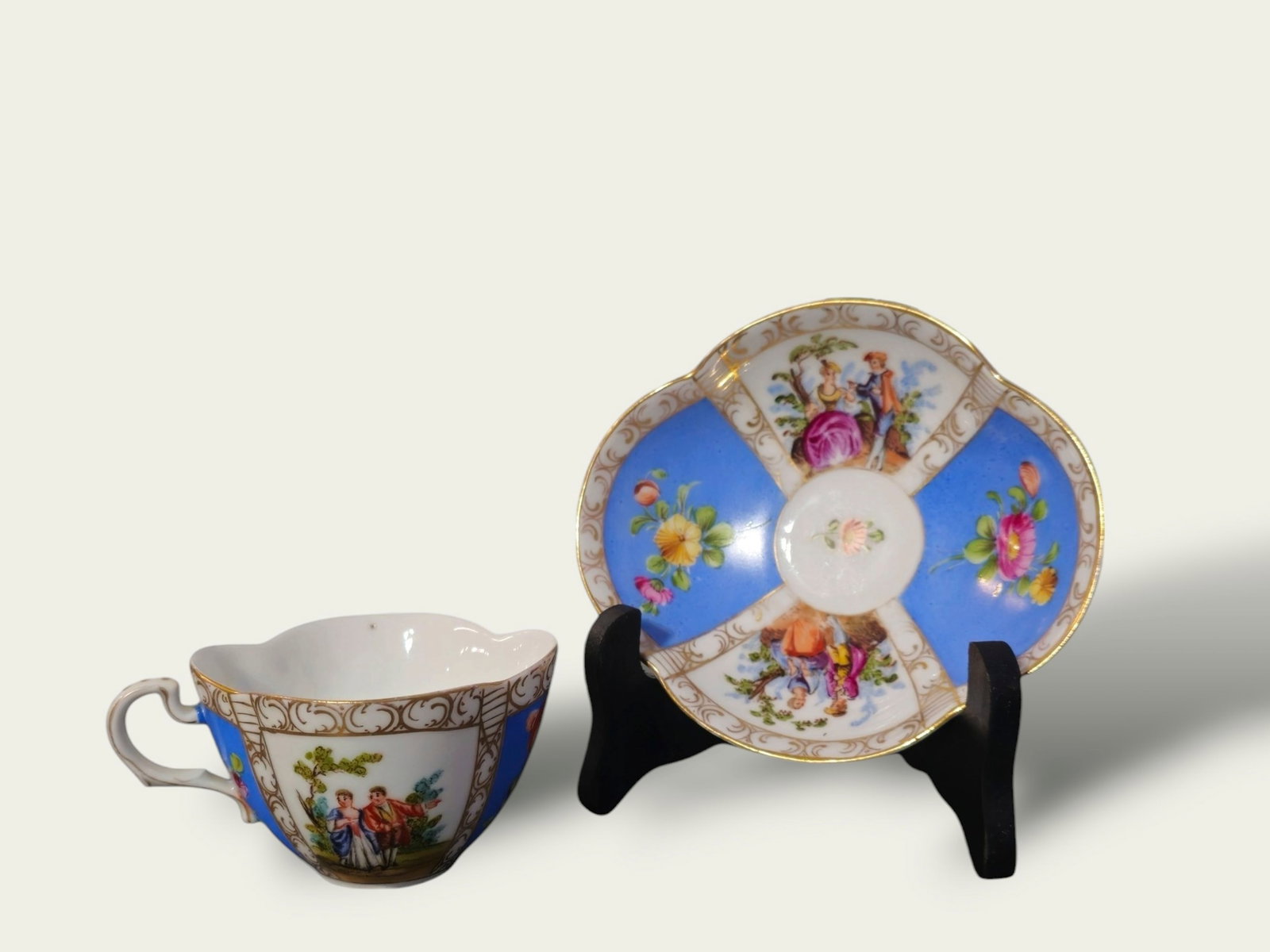 Helena Wolfsohn Dresden Demitasse Cup & Saucer: Helena Wolfsohn Dresden Demitasse Cup & Saucer, circa 1860. Blue panel Watteau. Augusta Rex mark to each. Quatrefoil shape with "Watteau" scenes of courting couples. Cup- 4w x 3 1/4d x 2h, Saucer- 5 1