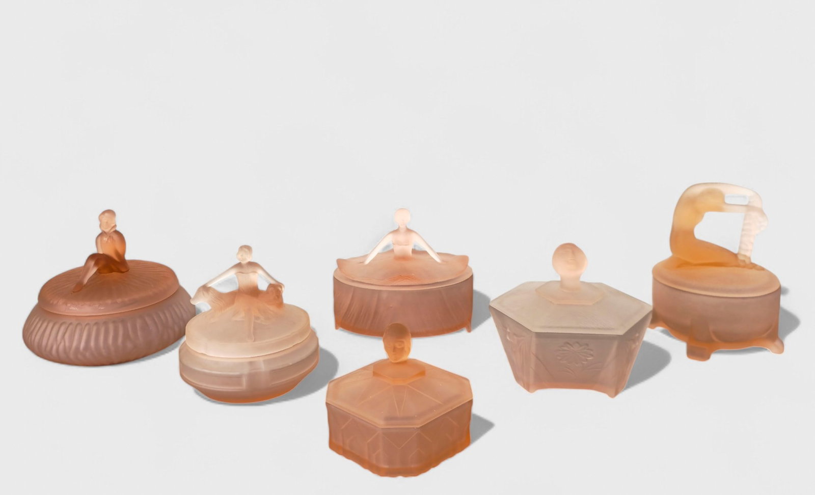 Assembled Pink Depression Glass Lidded Boxes: Assembled Pink Depression Glass Lidded Boxes, (6) total. (4) nude lid handle boxes, and (2) bust lid handle boxes. Largest- 6 1/2dia x 5 1/2h