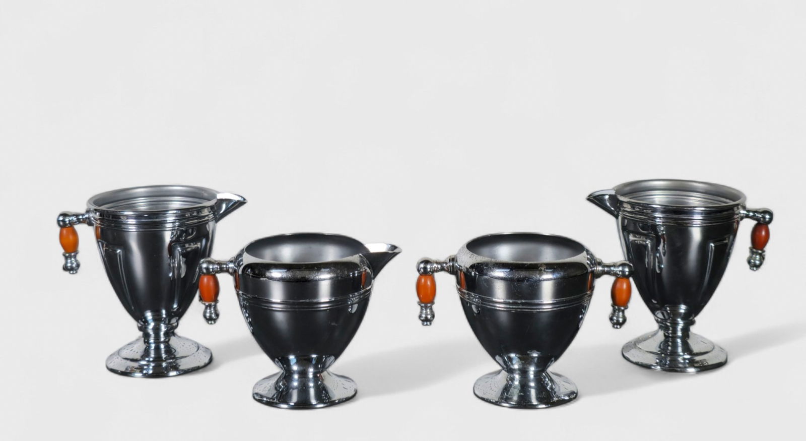 Keystone Art Deco Creamers & Sugars: Keystone Art Deco Creamers & Sugars, USA, 1930's. (3) creamers and (1) sugar. Manufacturer's mark to underside. Chrome plated metal and Bakelite. (4) Pieces total. 4 7/8w x 3 3/8d x 4 3/8h