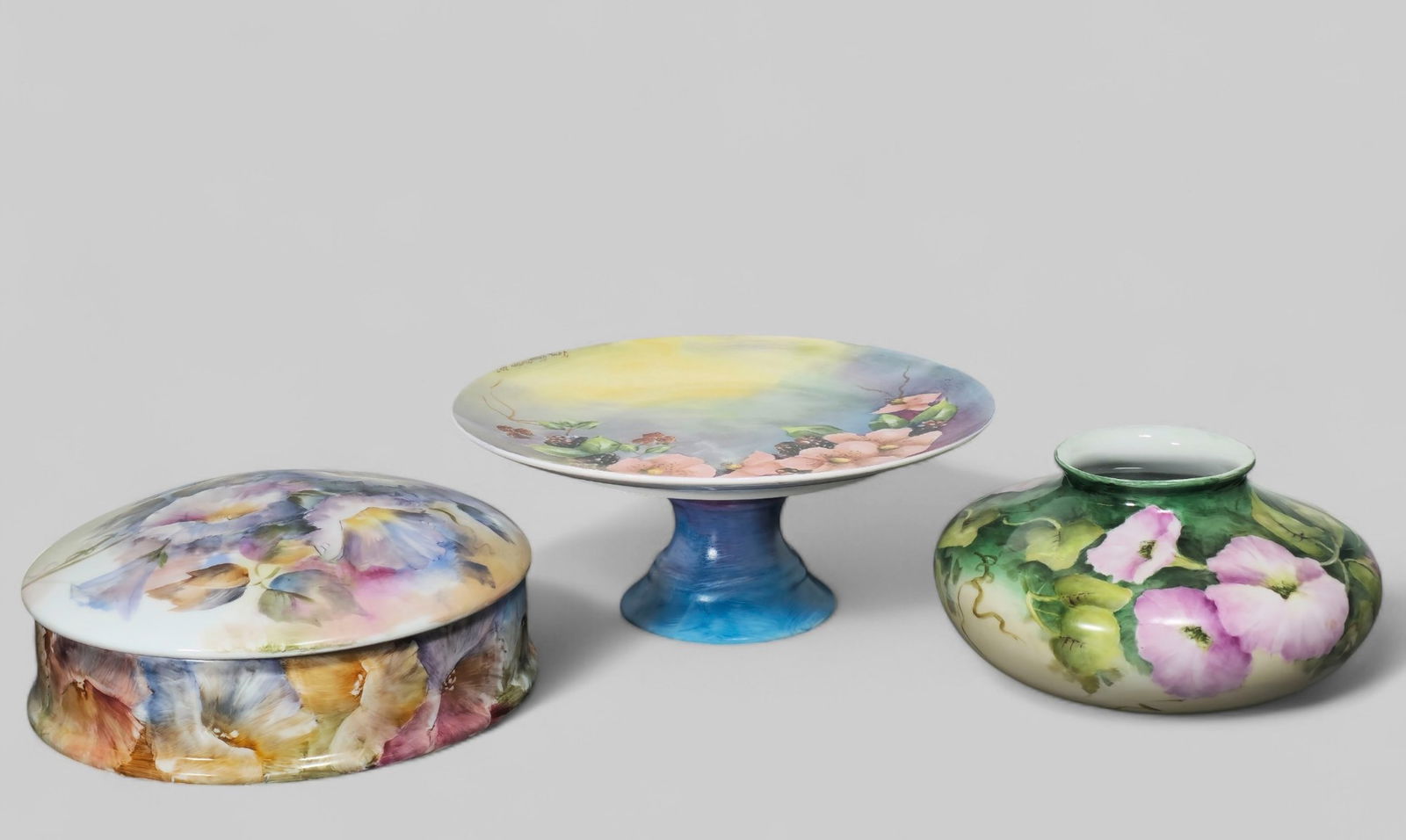 Assemble Tom Trauthwein Porcelain Grouping: Assemble Tom Trauthwein Porcelain Grouping. Compote, box and vase, 1 casserole, 4 dinner plates. All have hand decorated floral pattern. Signed to underside. Compote - 10 5/8 dia x 4 1/4h.