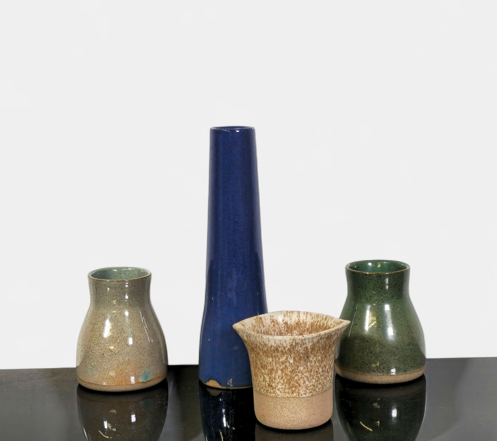 Gordon & Jane Martz Stoneware Group: Collection of four mid-century Martz stoneware vases in varied forms and glazes, including cylindrical, flared, and rounded shapes in blue, green, tan, and mottled brown finishes. Each exemplifies the
