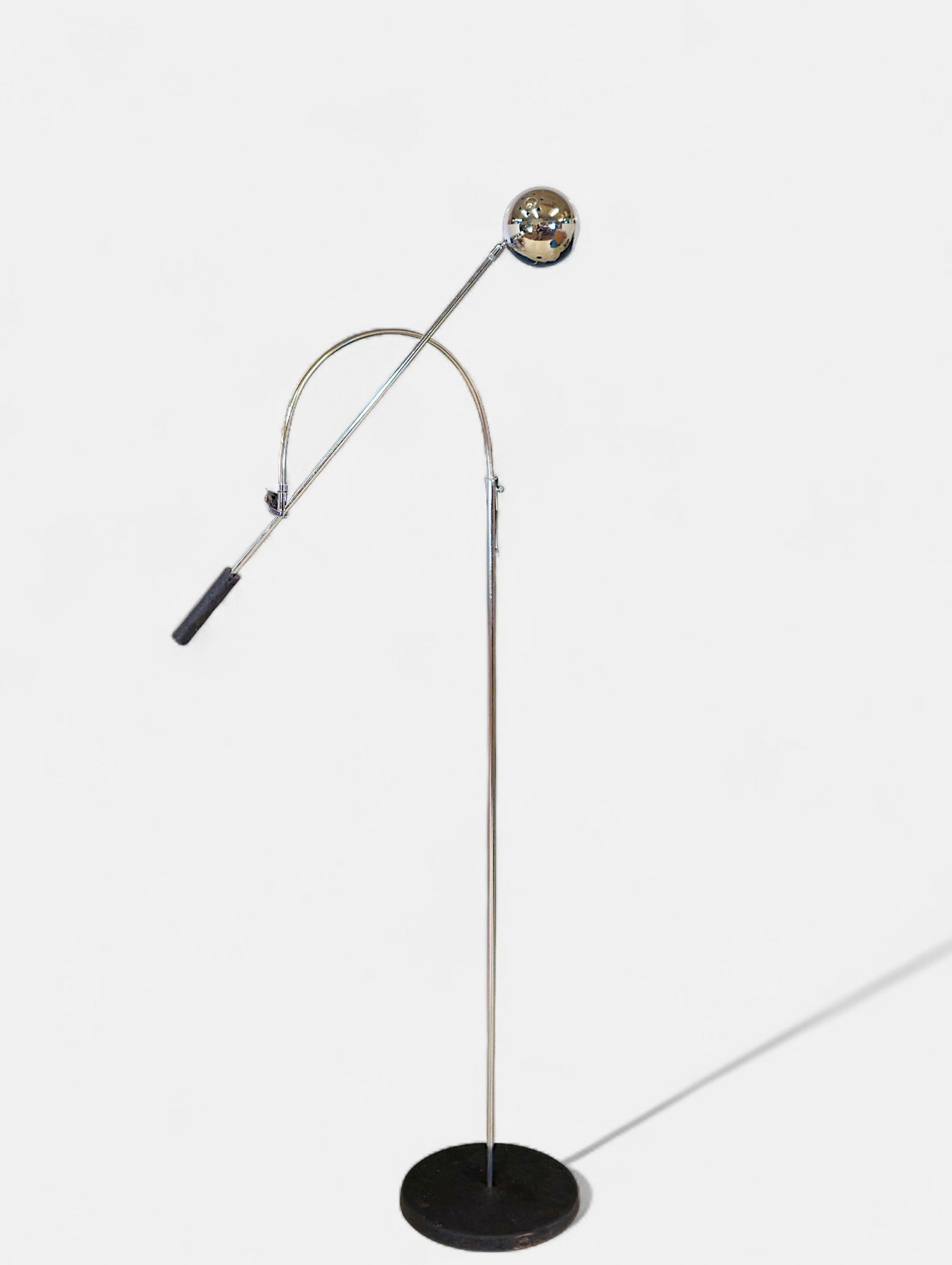 Robert Sonneman Adjustable Chrome Orb Floor Lamp: Mid-Century Modern adjustable floor lamp attributed to Robert Sonneman, featuring a polished chrome orb shade mounted on an arched support with a counterweighted handle and cylindrical black base. The
