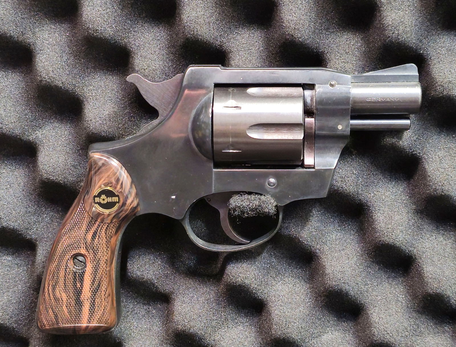 Röhm RG-series Snub-nose .38 Revolver: Röhm RG-series snub-nose revolver, chambered in .38 Special (“CAL .38 SPEZIAL”), German-made, with blued finish, 5-shot cylinder, and faux-wood checkered grips with Röhm medallion. Shows mod