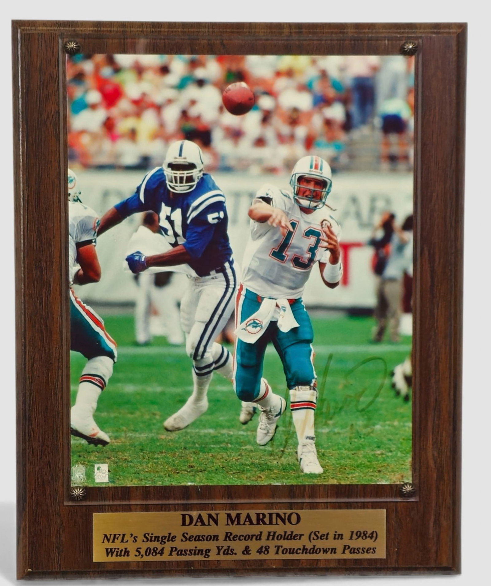 Dan “Laces Out” Marino 1984 (autographed photographic plaque): Autographed color photographic plaque depicting Hall of Fame quarterback Dan Marino (born 1961, USA) in action for the Miami Dolphins, highlighting his record-setting 1984 season with 5,084 passing ya