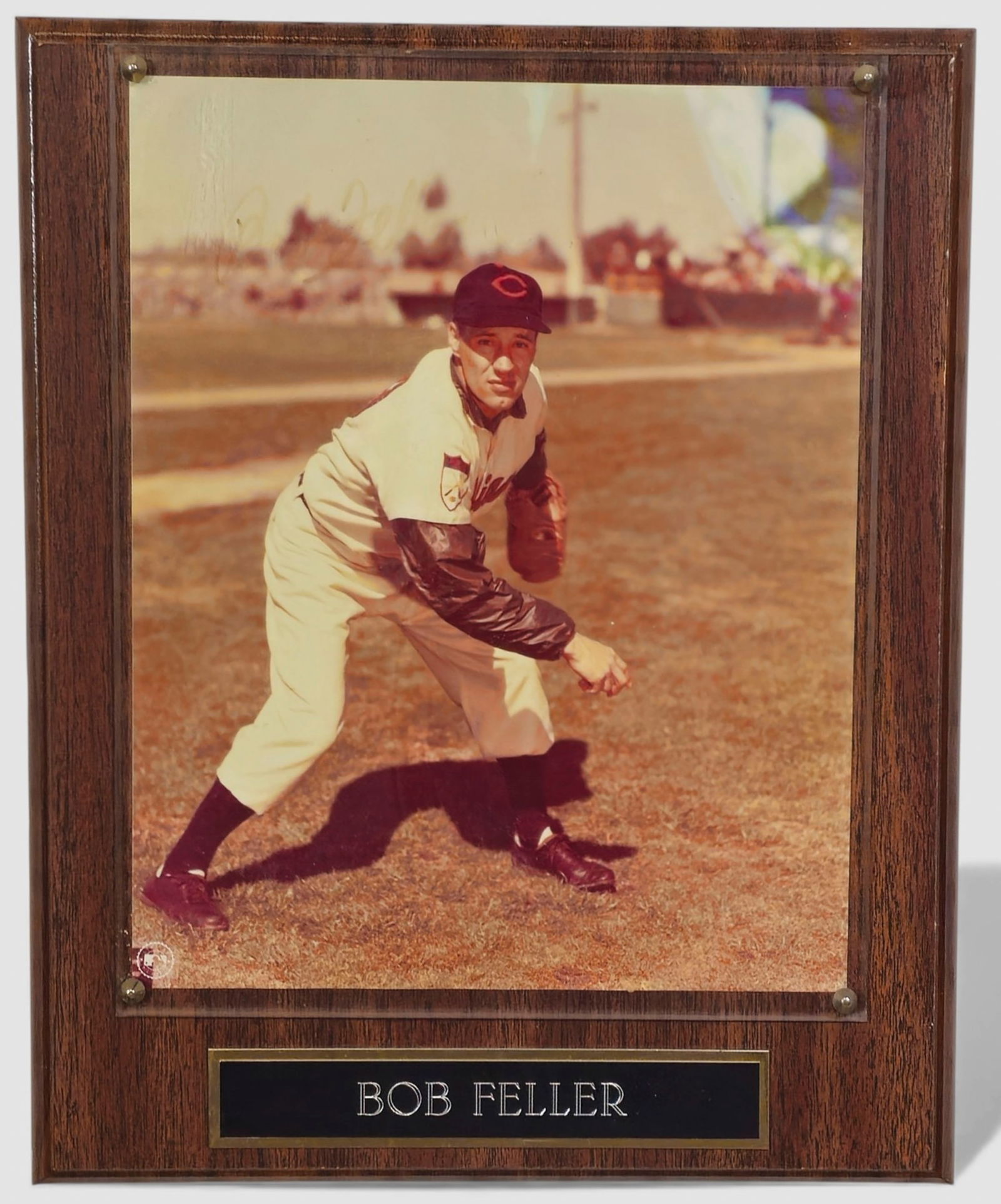 Bob Feller – Cleveland Indians Pitcher autographed photographic plaque: Autographed color photographic plaque depicting Hall of Fame pitcher Bob Feller (1918–2010, USA) in a classic pitching pose in Cleveland Indians uniform, mounted beneath acrylic on a wood-grain plaq