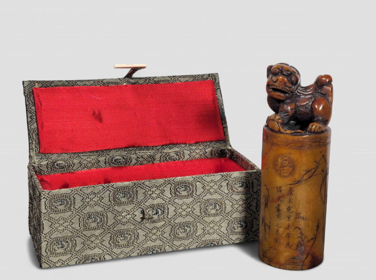 19th Century Chinese Soapstone Foo Dog Seal: 19th Century Chinese Soapstone Foo Dog Seal. Circa 1840-1860. Brown and light brown foo dog above an cylinder. Etched mountain scape and characters to cylinder. Carved seal to underside. 2 dia x 6h.