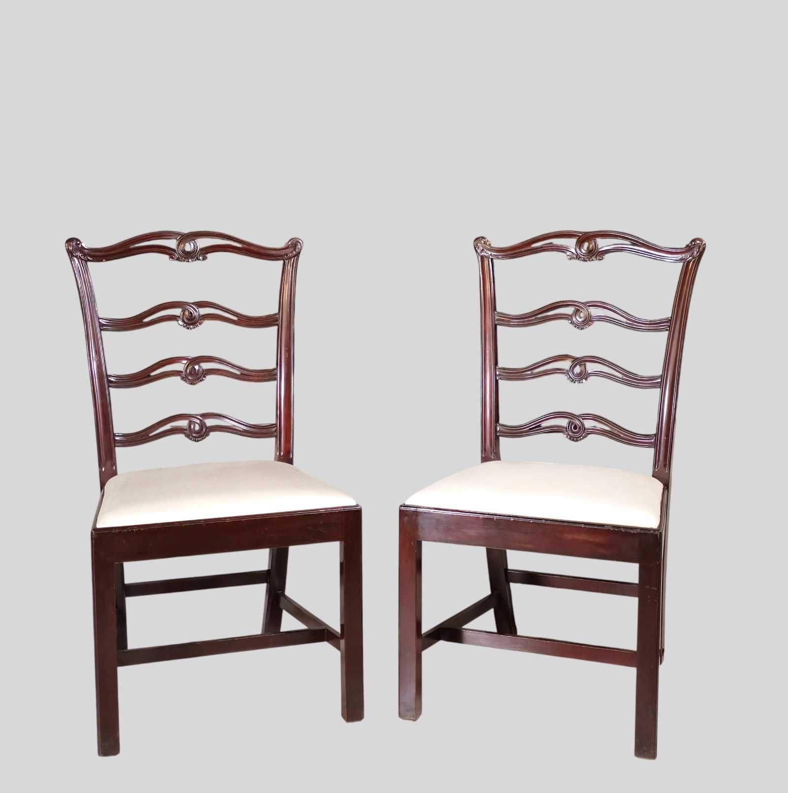 Centennial Chippendale Style Side Chairs: Centennial Chippendale Style Side Chairs. Pair. Circa 1900. Mahogany stain over maple. Curved crest rail over an sculptured ladder back. Slip in seats over straight legs with "H" stretchers. 21w x 21