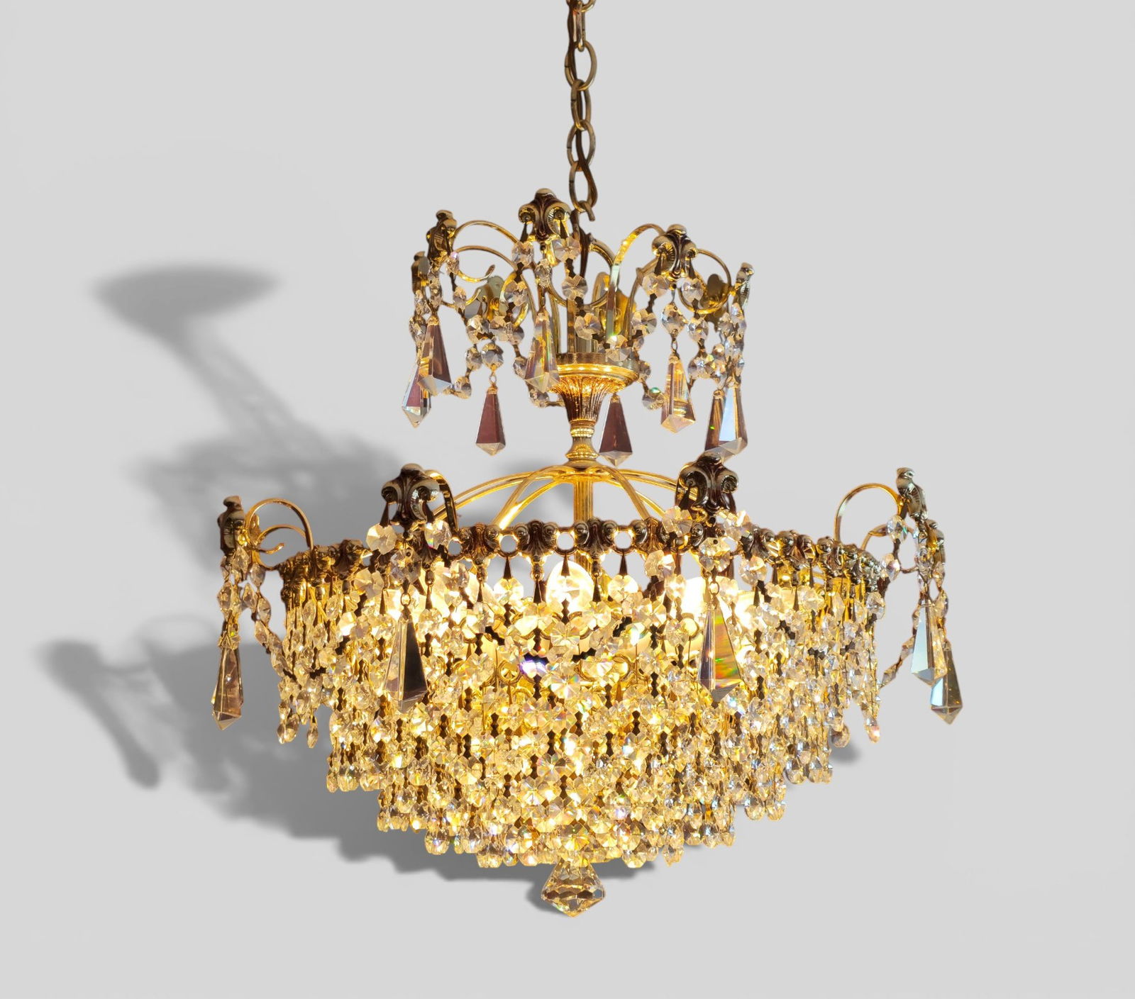 Schonbek Crystal Chandelier: Schonbek Crystal Chandelier. Fixture 1805-S. Schönbek gilt-metal and crystal chandelier, late 20th century, fitted with Swarovski Strass crystal prisms. Gilt scrolling frame supporting an circular